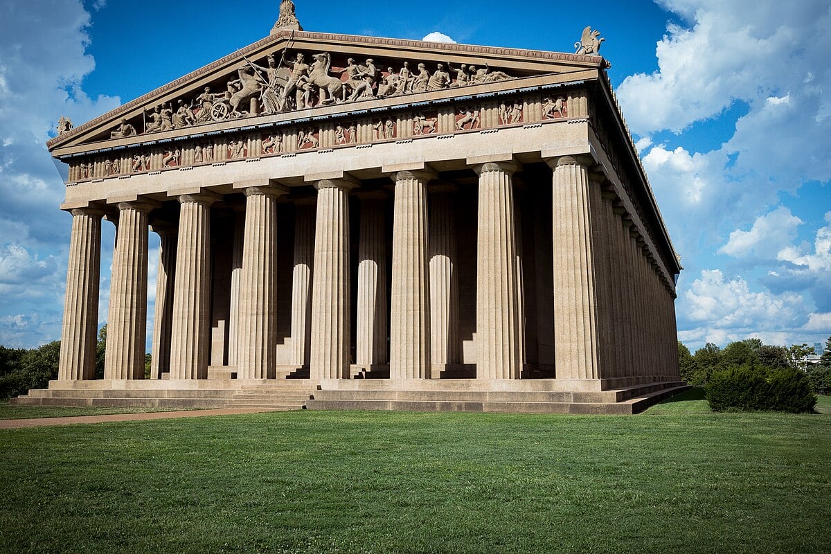 Parçalı bulutlu bir gökyüzü altında, Nashville'in Centennial Park'ındaki Parthenon'un gerçek boyutlu bir kopyası.