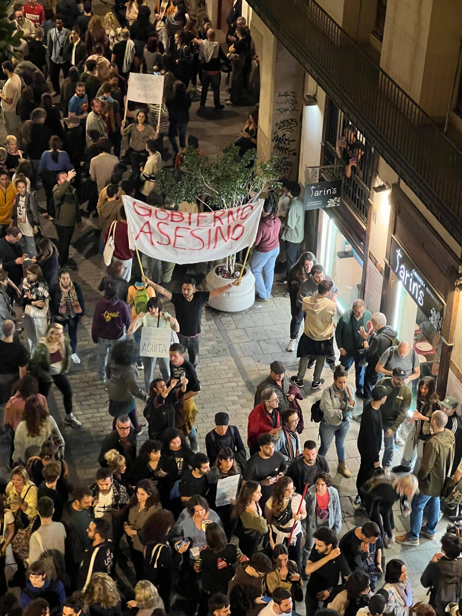 Elinde “hükümet suikastçıları” yazan bir pankart tutan bir protestocu.